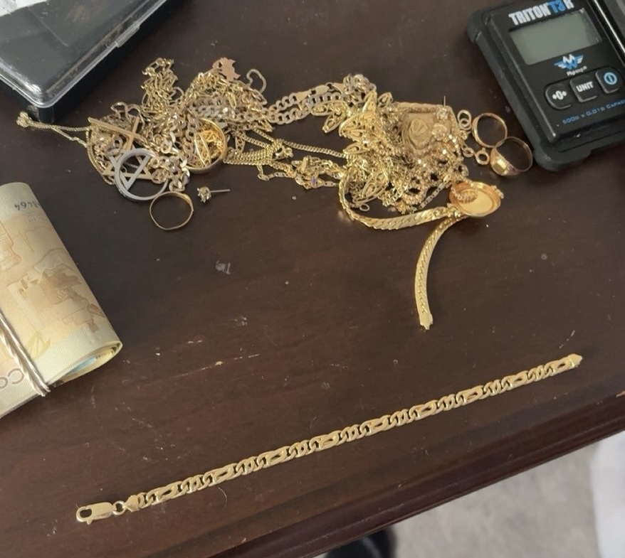 Gold chains on a dark table with part of a scale and Canadian banknotes visible