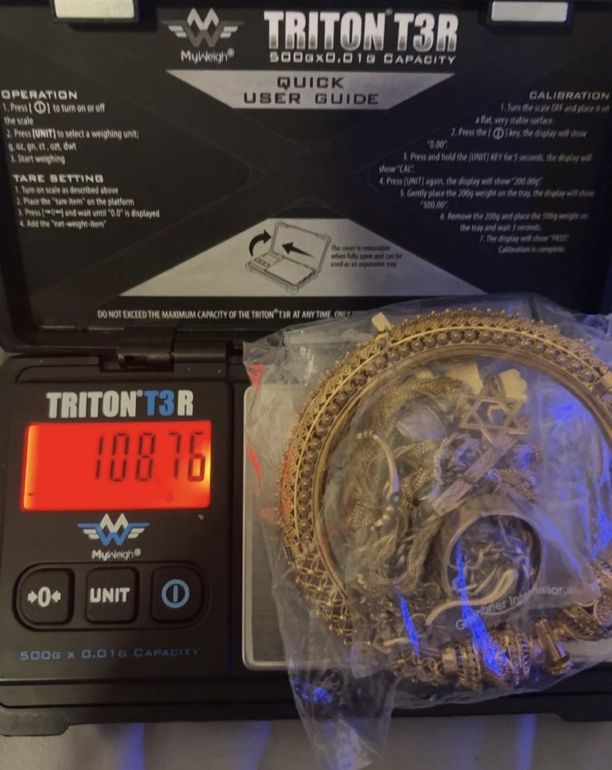 Gold chains in a clear bag beside the red display of a digital scale