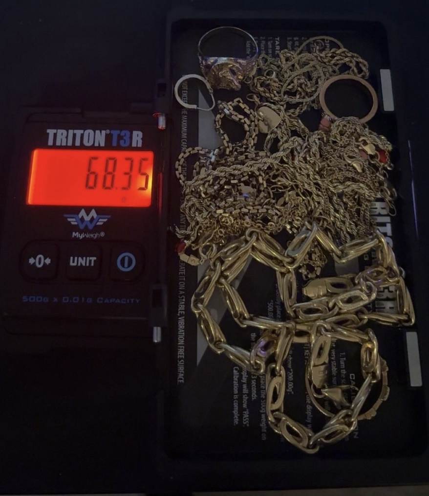 A pile of gold chains on a scale beside its red display