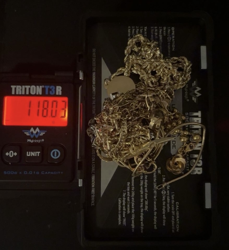 Mixed gold chains and pendants on the tray of a digital scale