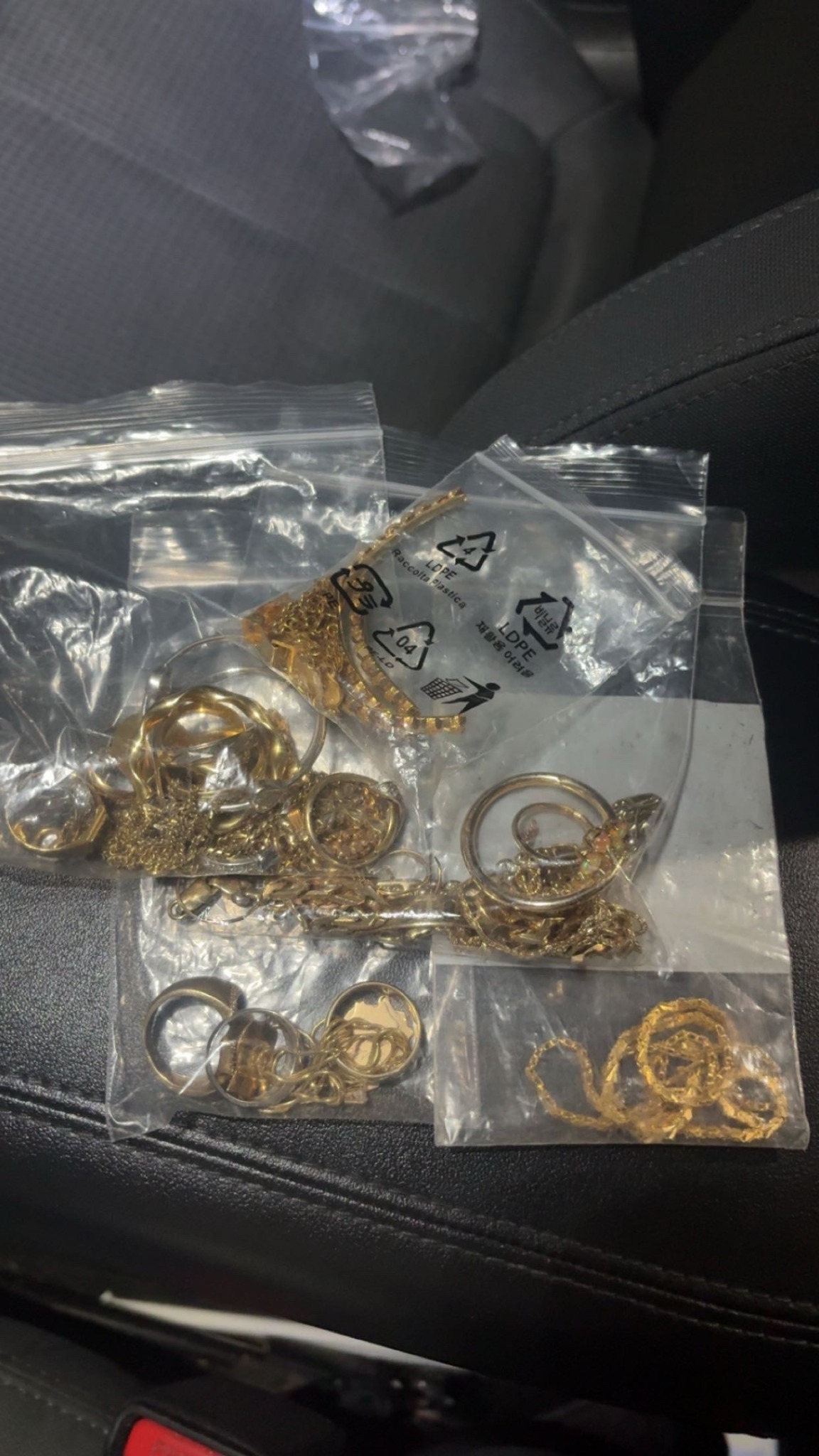 Several clear bags of gold rings and chains inside a vehicle