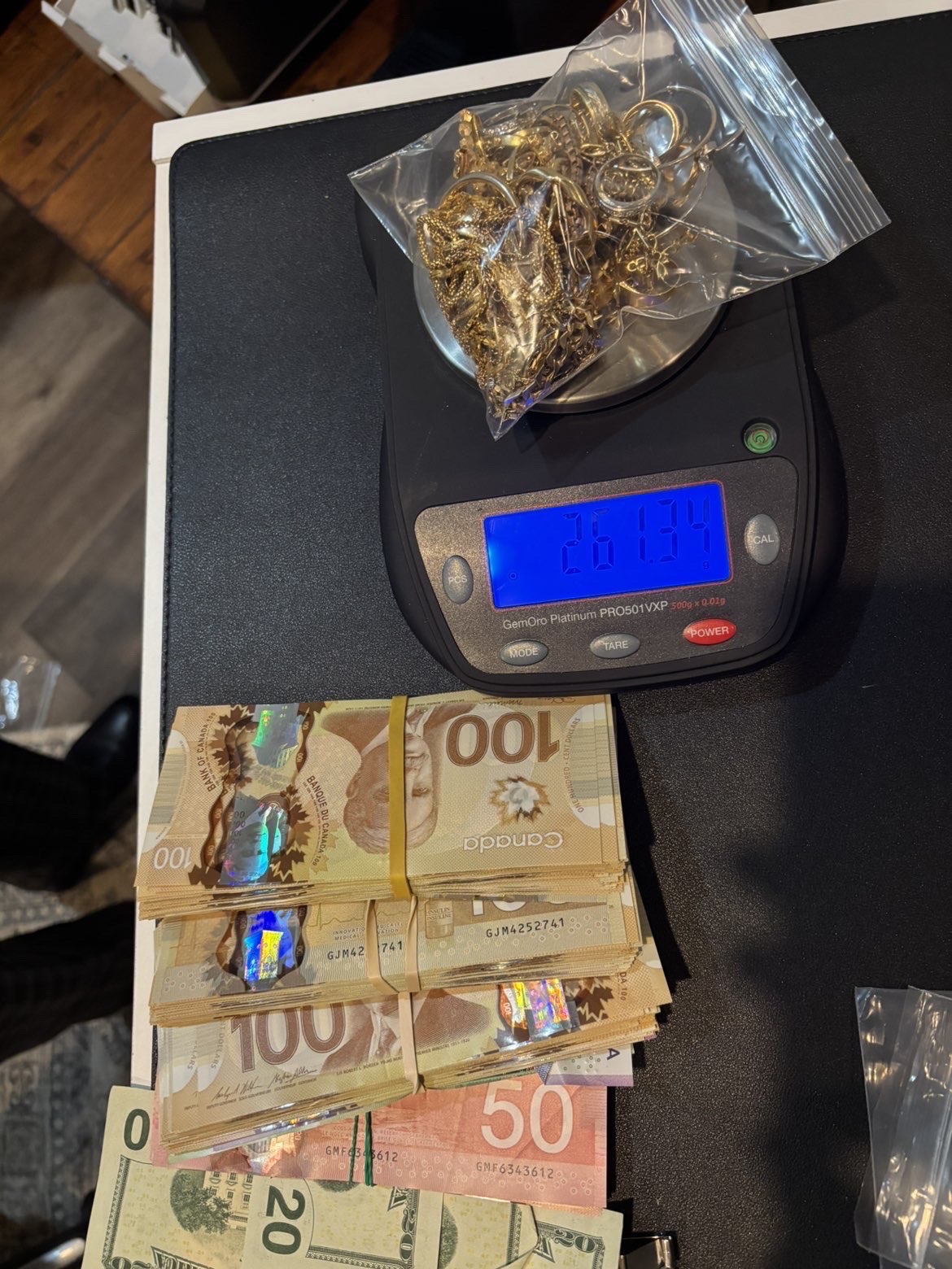 Bagged gold on a digital scale beside stacks of Canadian banknotes