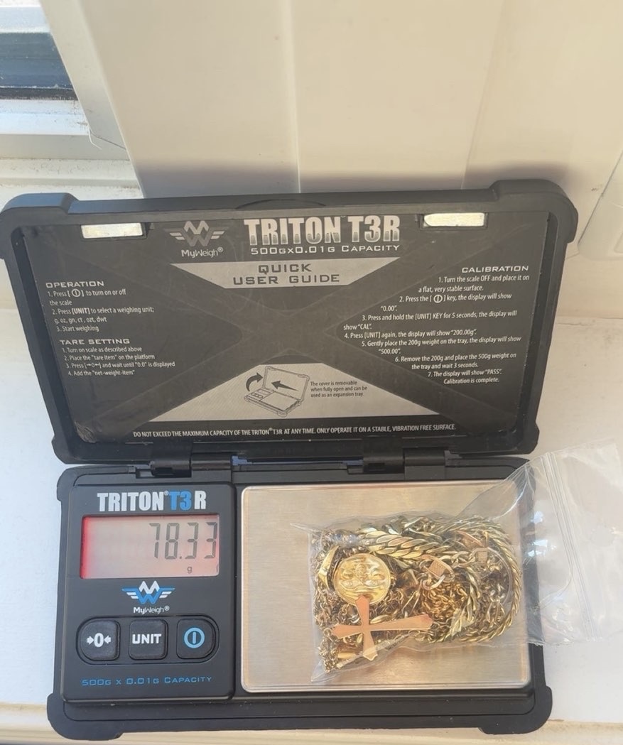 Gold chains and pendants on the tray of an open digital scale